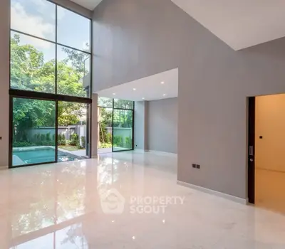 Spacious modern living room with floor-to-ceiling windows and pool view