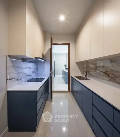 Modern kitchen with sleek cabinetry and marble backsplash in a contemporary apartment.