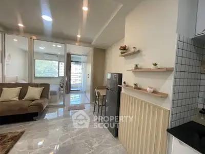 Modern open-plan living room with sleek kitchen and cozy bedroom, featuring stylish decor and natural light.