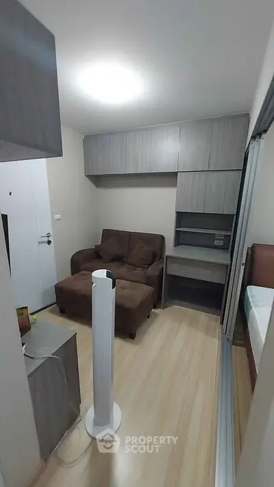 Cozy living room with modern furniture and wooden flooring in a compact apartment.