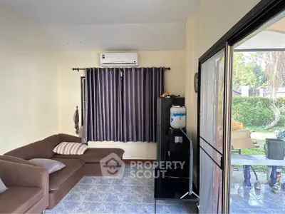 Cozy living room with brown sectional sofa, air conditioning, and garden view through sliding doors.