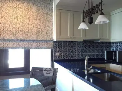Elegant kitchen with patterned backsplash and modern lighting, featuring a sleek countertop and dining area.