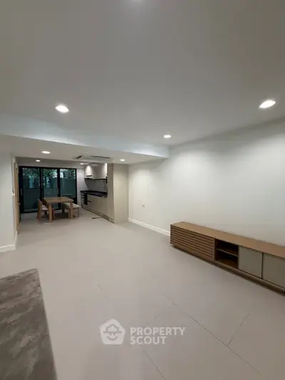 Spacious open-plan living room with modern kitchen and dining area, featuring sleek design and ample natural light.