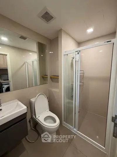 Modern bathroom with glass shower and sleek fixtures in a contemporary apartment.