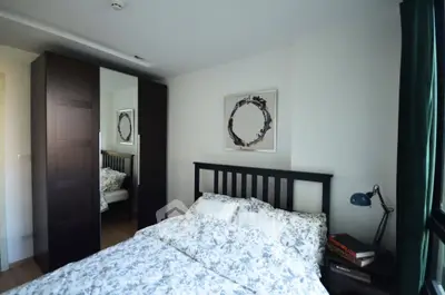 Cozy bedroom with stylish decor and ample natural light, featuring a comfortable bed and modern wardrobe.