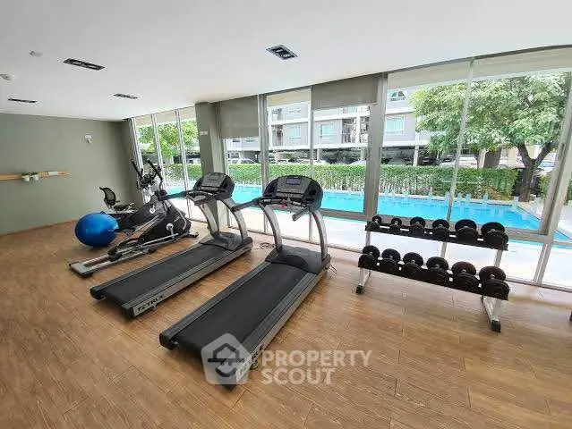 Modern gym with treadmills and pool view in luxury apartment complex