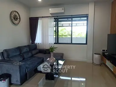 Modern living room with sleek furniture and large window offering natural light.