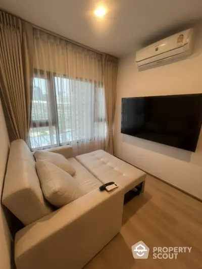 Cozy living room with modern sofa, large TV, and air conditioning in a stylish apartment.