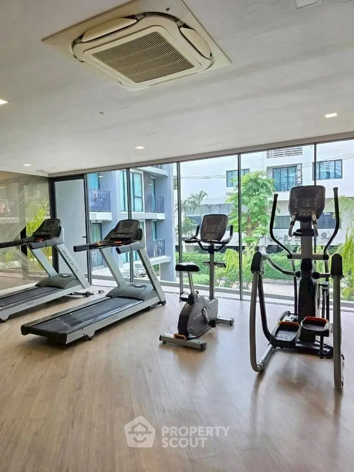 Modern gym with cardio equipment and garden view in luxury apartment complex.
