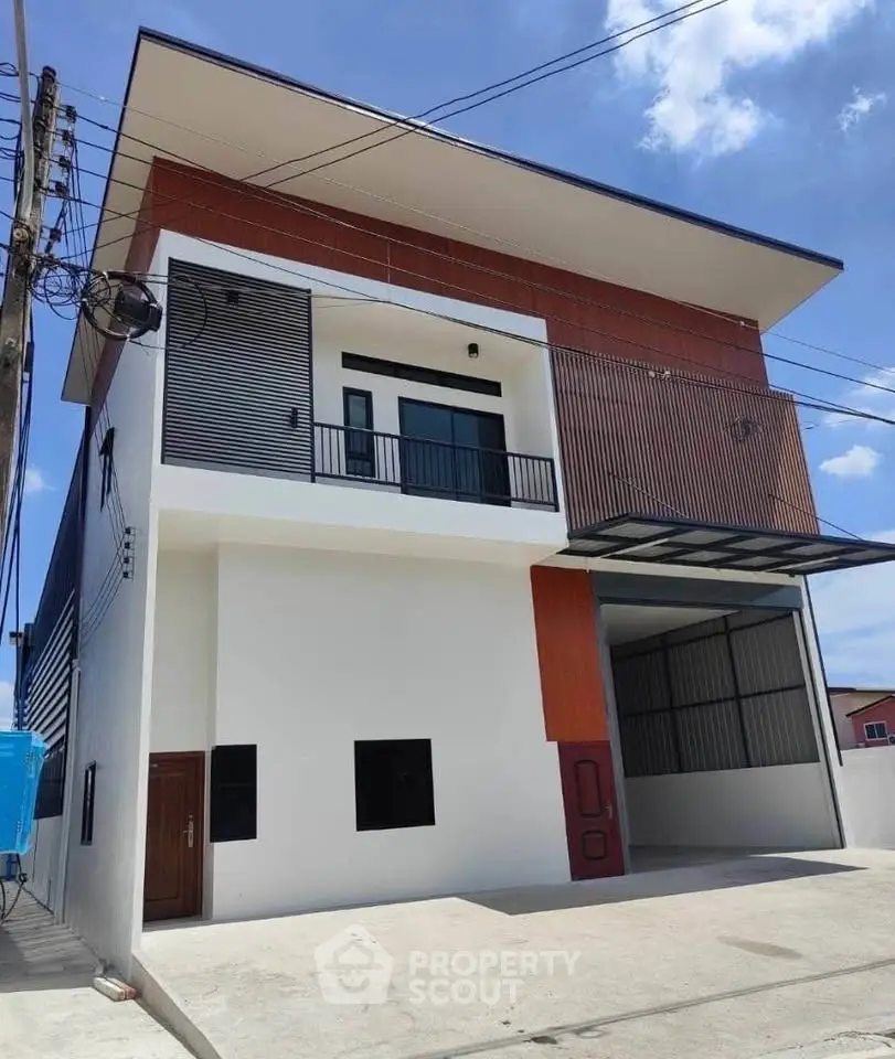 Modern three-story building with sleek design and spacious balcony under clear blue sky.