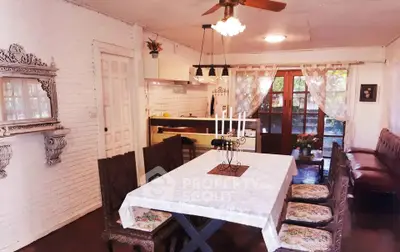 Charming dining area with rustic decor and open kitchen layout, featuring elegant wooden furniture and natural light.