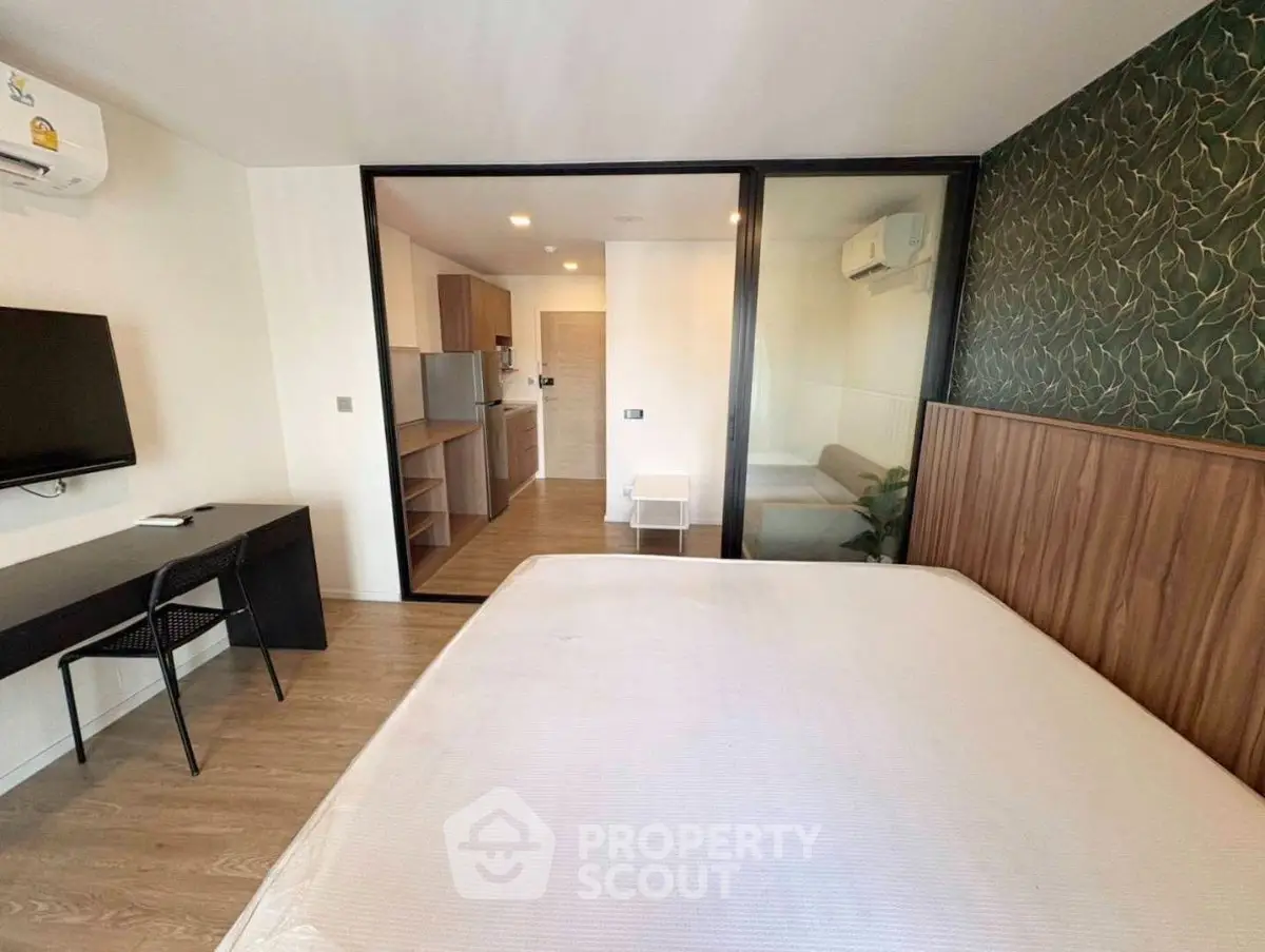 Modern bedroom with glass partition, stylish decor, and open view to kitchen area.