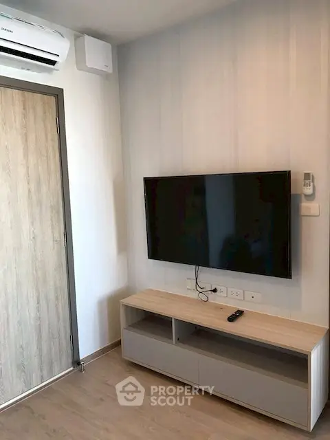 Modern living room with wall-mounted TV and sleek wooden cabinet.