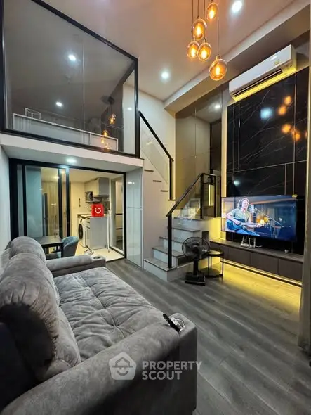 Modern living room with mezzanine, stylish lighting, and sleek kitchen in a contemporary apartment.