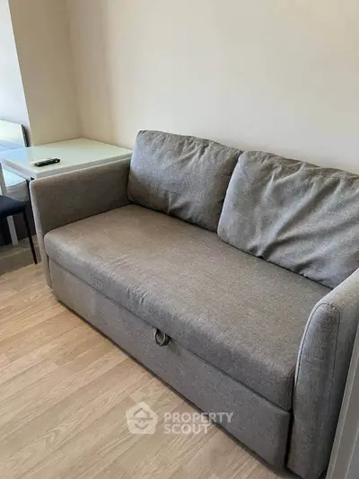 Cozy living room with a comfortable gray sofa and wooden flooring, perfect for relaxation.