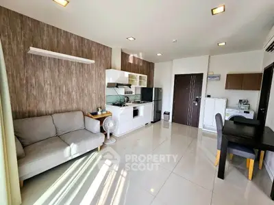 Modern open-layout living room with sleek kitchen and dining area, featuring stylish decor and ample natural light.