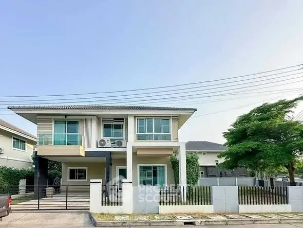 Modern two-story house with balcony and spacious driveway in suburban neighborhood.