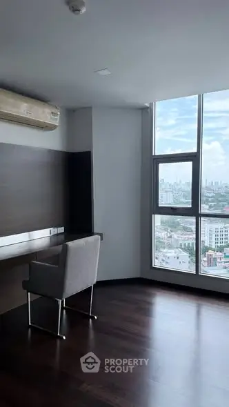 Modern study room with large window offering stunning city views, featuring sleek wooden flooring and a comfortable chair.