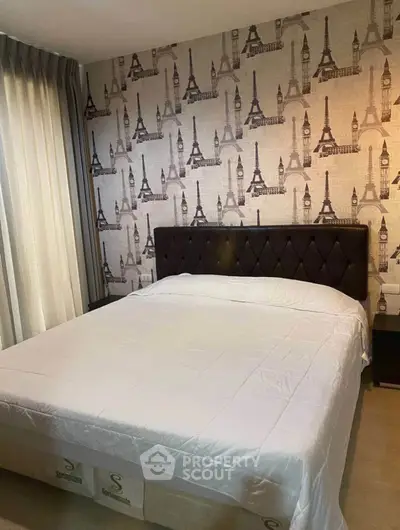 Cozy bedroom with elegant wallpaper and plush headboard in modern apartment.