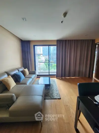 Spacious living room with modern sofa and city view balcony.