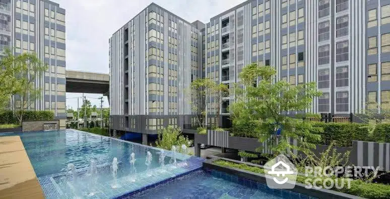 Modern apartment complex with pool and lush greenery, offering a serene urban living experience.