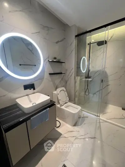 Luxurious modern bathroom with marble tiles, illuminated mirror, and sleek shower design.