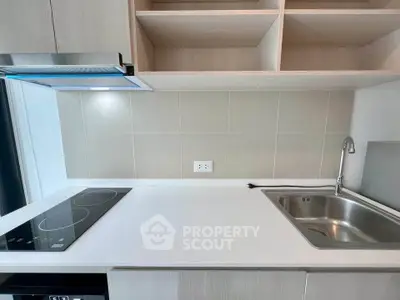 Modern kitchen with sleek induction cooktop and stainless steel sink, ideal for contemporary living.