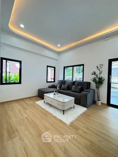 Modern living room with stylish sofa and elegant lighting, featuring large windows and wooden flooring.