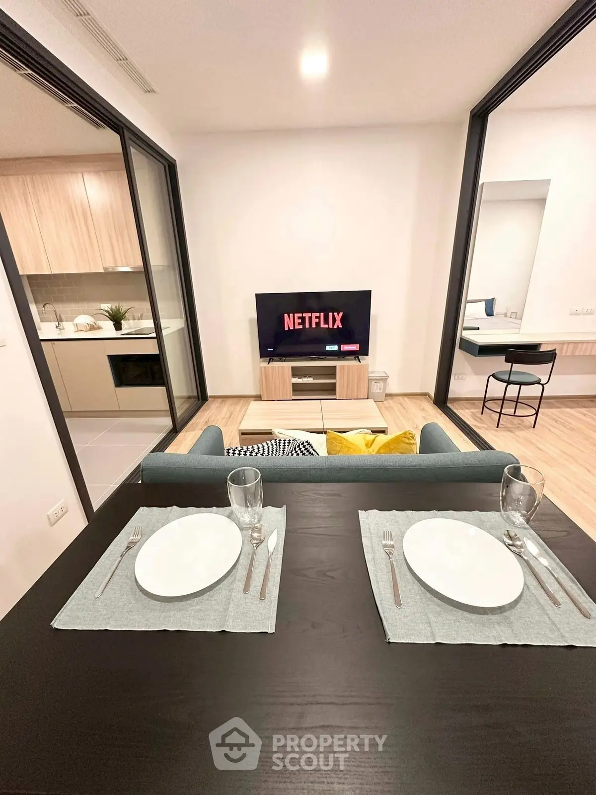 Modern living room with open kitchen and dining area, featuring stylish decor and a cozy ambiance.