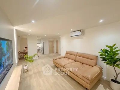 Spacious modern living room with tan leather sofa and sleek wooden flooring