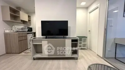 Modern living room with sleek TV stand and compact kitchen area.