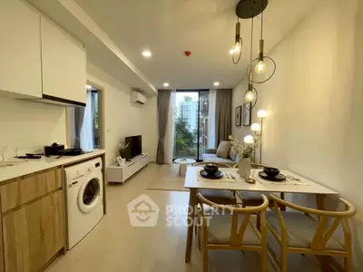 Modern open-plan living room with dining area and washing machine, featuring stylish lighting and decor.