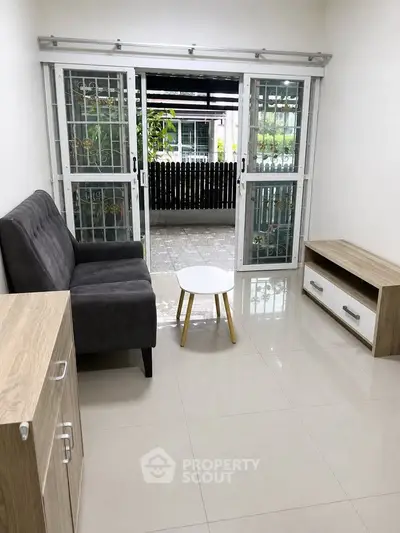 Cozy living room with sliding glass doors leading to a patio, featuring modern furniture and natural light.
