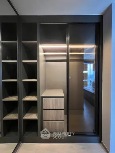 Modern walk-in closet with sleek shelving and drawers in a stylish apartment.