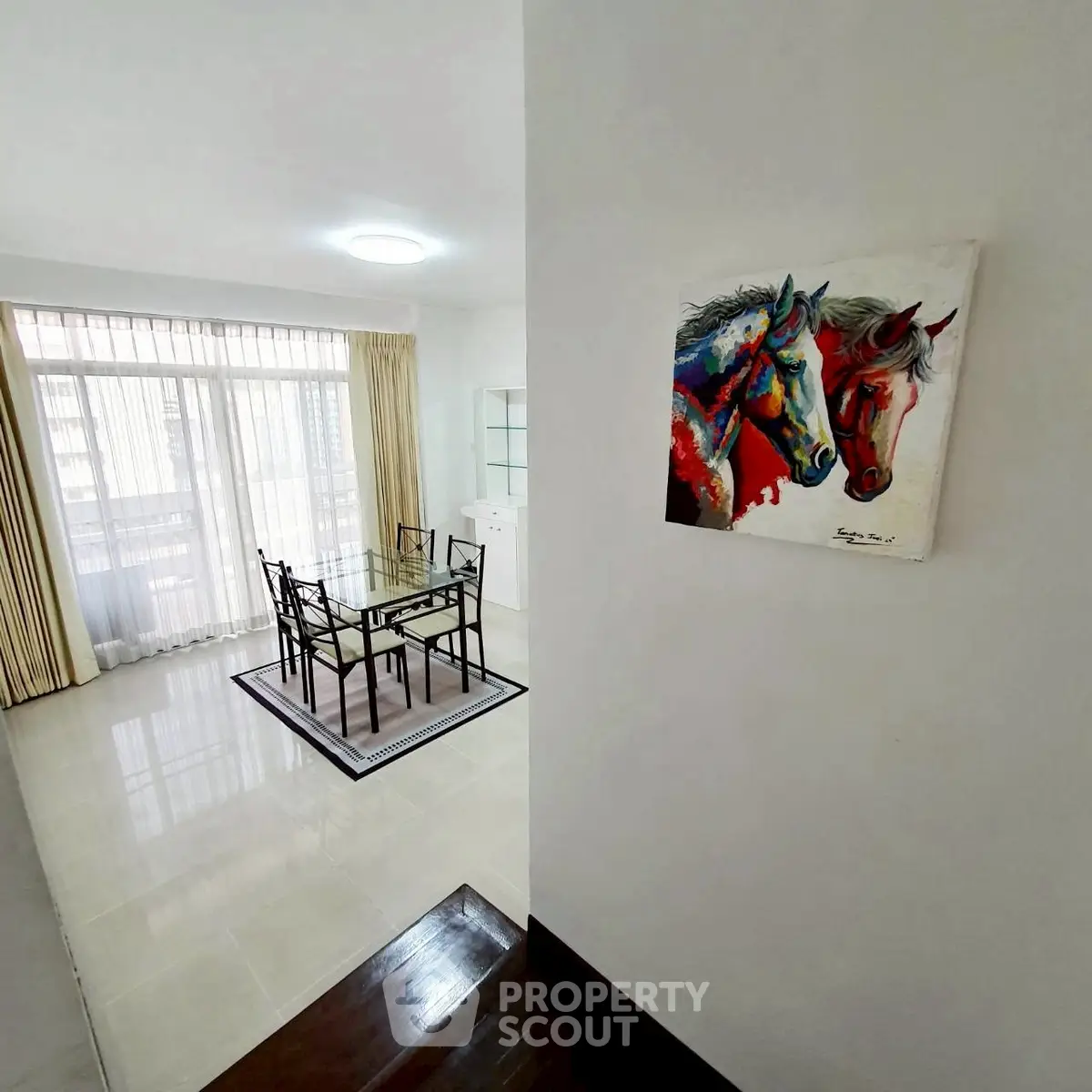 Bright dining area with modern glass table and horse painting, perfect for stylish living.