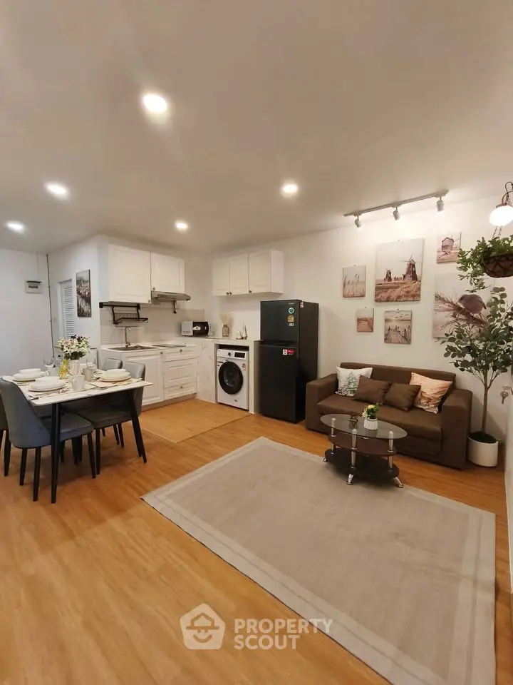 Modern open-plan living room with kitchen and dining area, featuring stylish decor and appliances.
