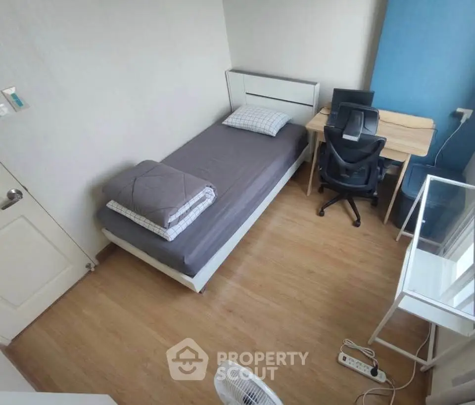 Cozy bedroom with single bed, desk, and chair, perfect for a student or professional.
