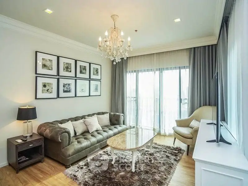 Elegant living room with chandelier, plush sofa, and large windows for natural light.