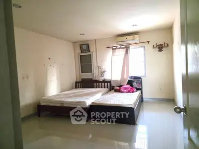 Spacious bedroom with twin beds and air conditioning in a well-lit room.