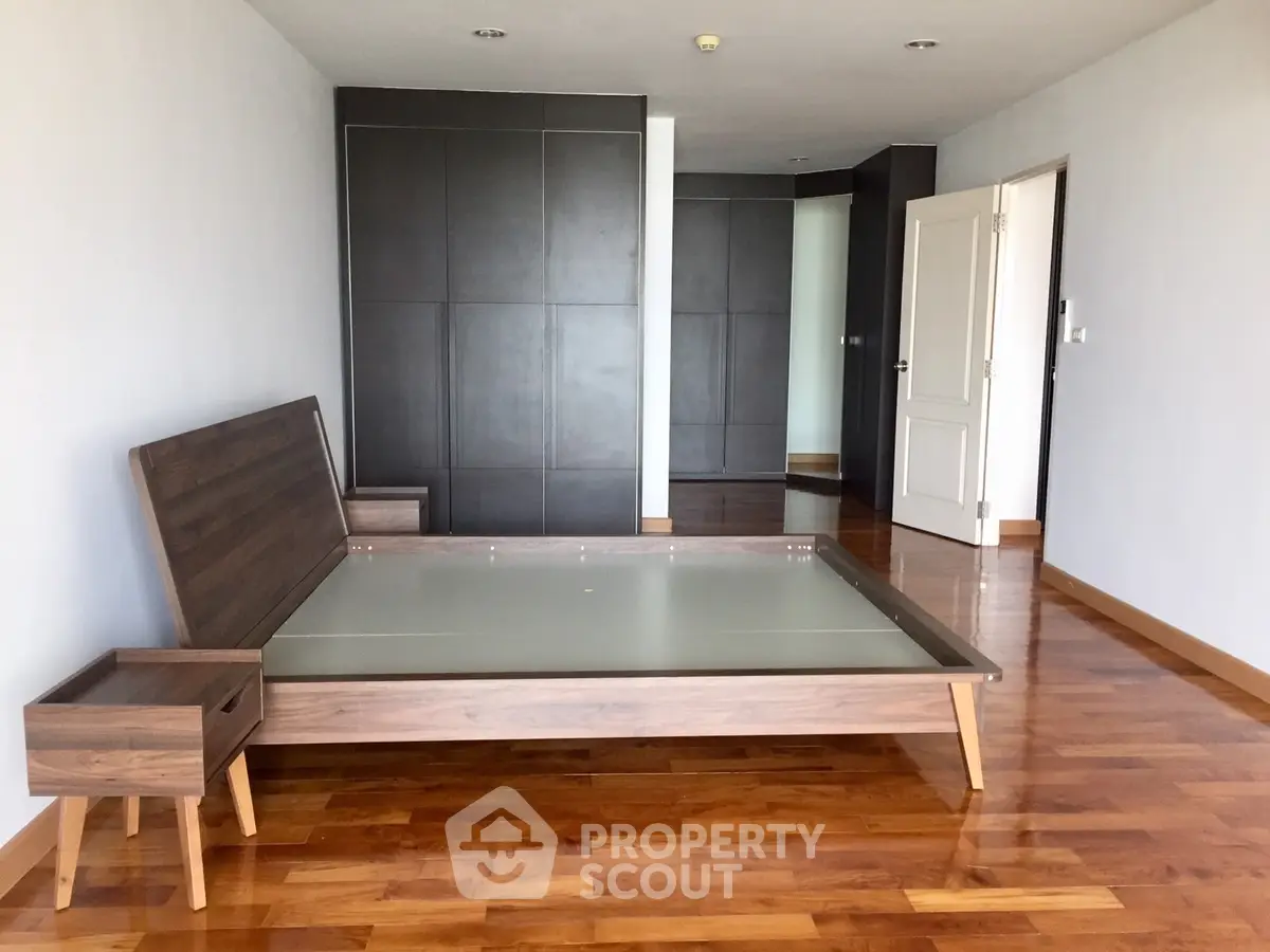 Spacious bedroom with modern wooden flooring and sleek furniture design.