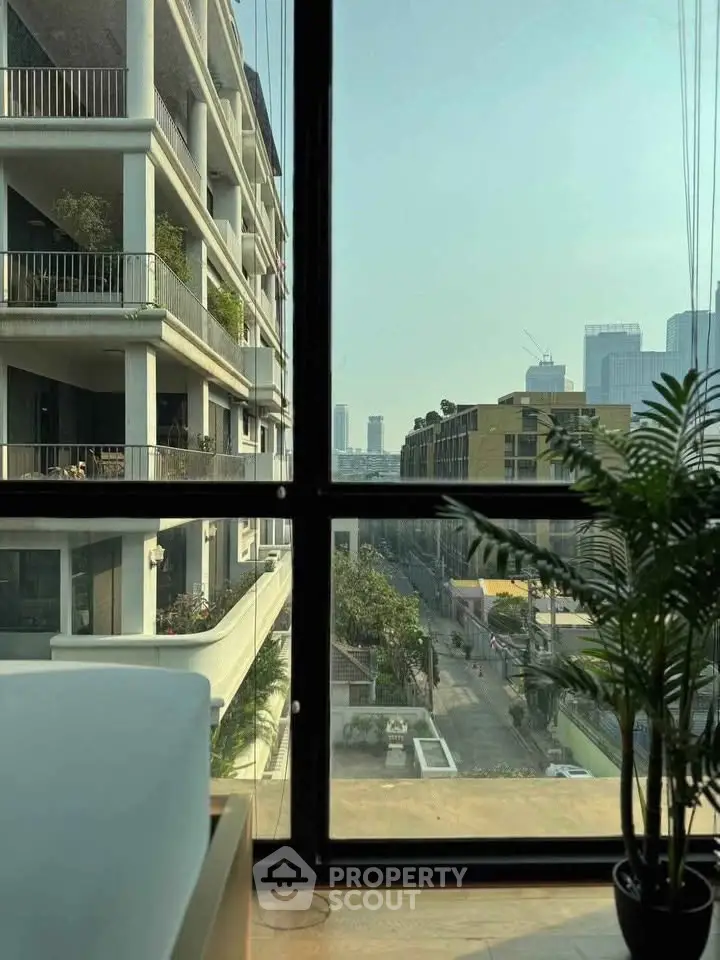 Stunning urban view from modern apartment window with lush greenery and city skyline.