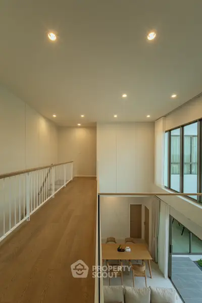 Modern duplex interior with open living area and dining space, featuring large windows and wooden flooring.