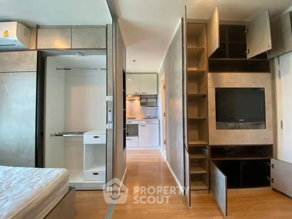 Modern apartment interior with open closet and kitchen view, featuring sleek design and wooden flooring.