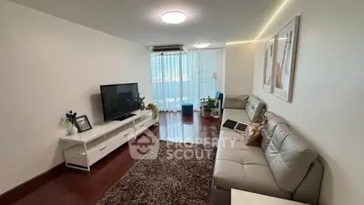 Spacious living room with modern decor and natural light, featuring a cozy seating area and entertainment center.