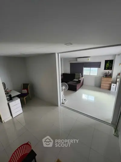Modern living room with open layout and study area, featuring sleek furniture and bright lighting.