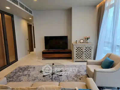 Elegant living room with modern furniture and large TV, featuring a cozy ambiance and stylish decor.