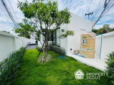 Modern white house with lush green garden and tree, showcasing contemporary exterior design.