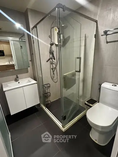 Modern bathroom with glass shower enclosure and sleek fixtures in contemporary apartment.