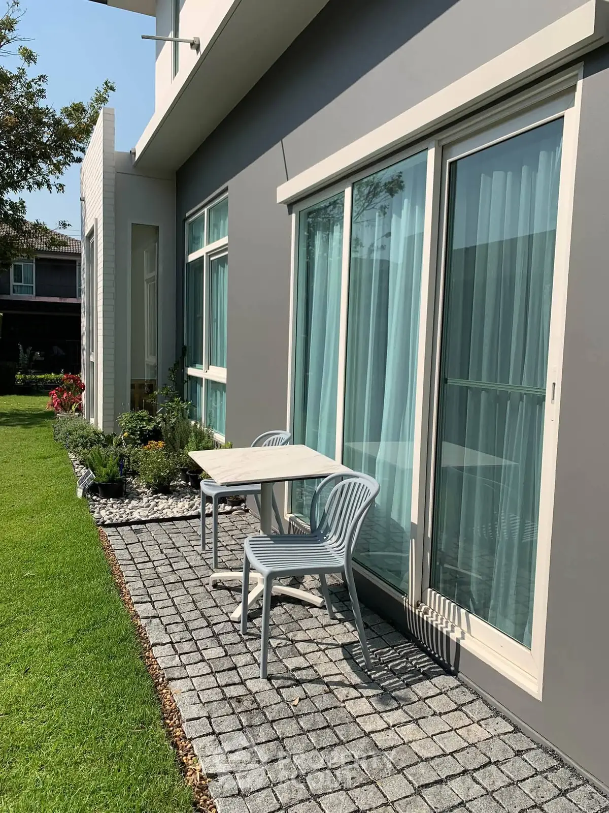 Charming garden patio with modern outdoor seating and lush greenery, perfect for relaxation and entertaining.