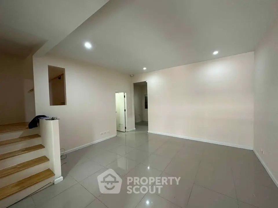 Spacious empty living room with modern tile flooring and recessed lighting, perfect for customization.